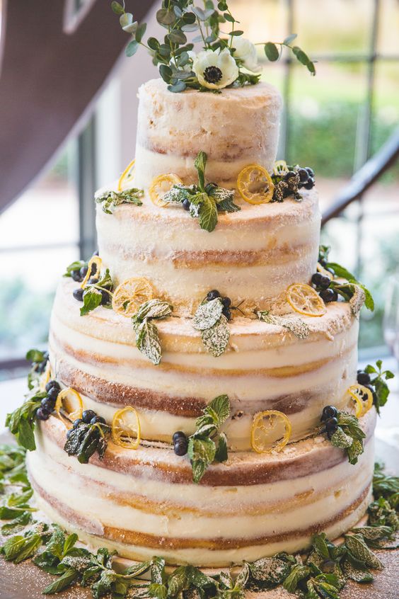 a large striped naked wedding cake with citrus, berries and mint plus white blooms and greenery is amazing
