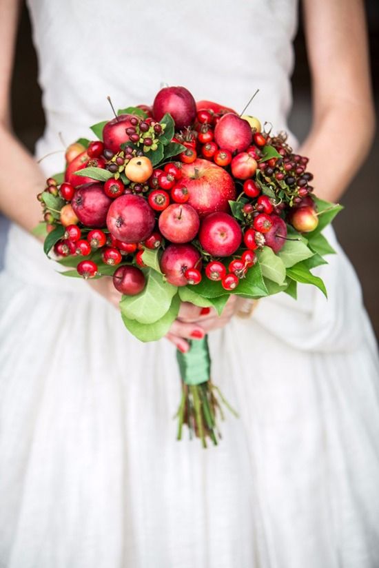 a lovely and creative wedding bouquet compose of apples and various berries plus greenery for a bright red fall wedding