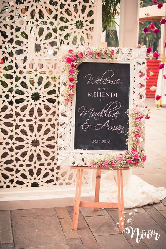 a lovely chalkboard sign with calligraphy, in a beautiful white frame decorated with white and pink blooms