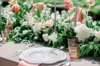 a lovely secret garden wedding tablescape with muted and printed linens, a lush greenery and bold floral runner plus tall candles