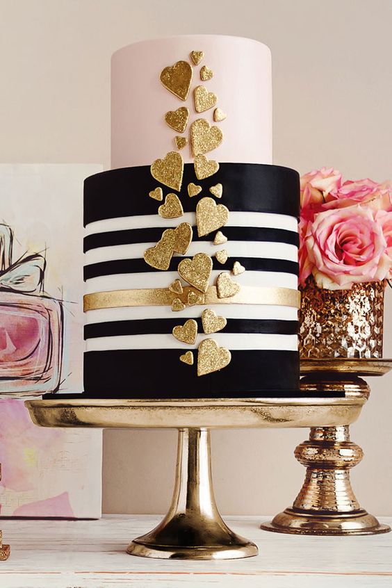 a modern glam wedding cake with a black and white striped and a pink tier plus gold glitter heart decor is amazing