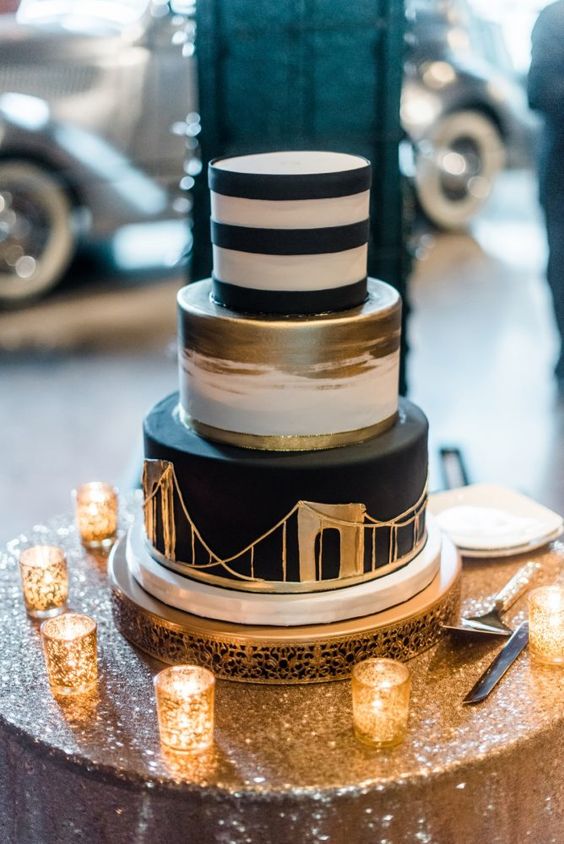 a modern wedding cake with a black and white striped tier, a white and gold one, a black tier with a gold bridge painted is unusual