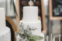 a modern white wedding cake with eucalyptus and ferns plus a topper is a chic idea