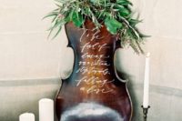 a musical instrument dressed up with greenery can substitute any usual sign and make your wedding decor more special