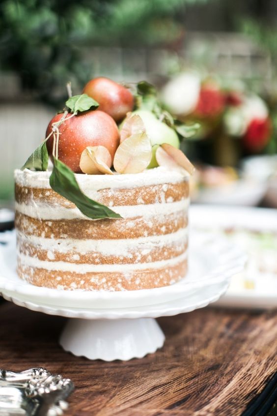 a naked wedding cake topped with apples, greenery and leaves will be a gorgeous solution for a fall wedding