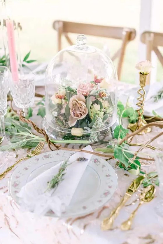 a neutral and chic garden wedding centerpiece of blush and pink blooms and greenery in a cloche is a veyr playful idea