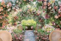 a pastel flower garden wedding ceremony space with greenery and pink bloom arches and floral arrangements on the ground