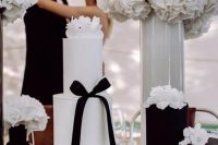 a pretty arrangement of wedding cakes with black cakes with white blooms and a white cake with white blooms and a black ribbon bow