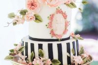 a pretty spring or summer wedding cake with a black and white vertical stripe tier and a white one with floral decor, with pnk sugar and fresh blooms