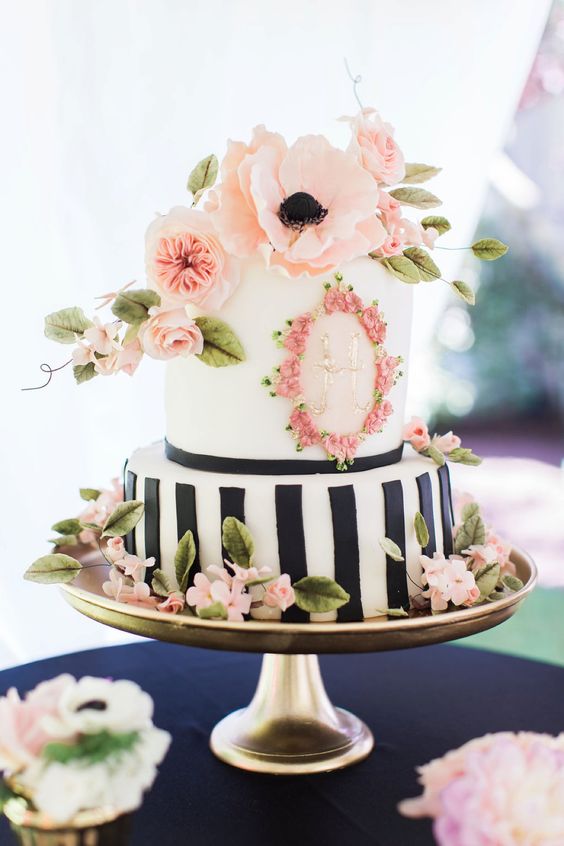 a pretty spring or summer wedding cake with a black and white vertical stripe tier and a white one with floral decor, with pnk sugar and fresh blooms