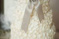 a quirky neutral wedding cake with sugar flowers, a grey ribbon bow with an embellished brooch is a lovely idea for a vintage wedding