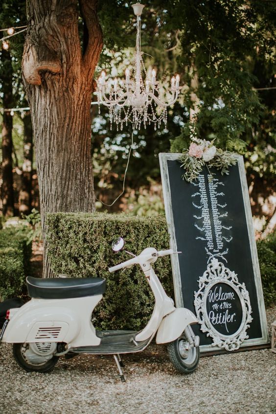 a refined chalkboard seating plan with chalking, calligraphy and a refined white frame, with neutral blooms and greenery