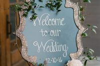 a refined chalkboard sign accented with a lovely splatter cutout frame, with greenery and some blooms is a lovely idea for a wedding
