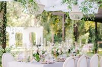 a refined garden wedding reception with lilac and pink linens, beaded chandeliers and greenery climbing, neutral and pink blooms