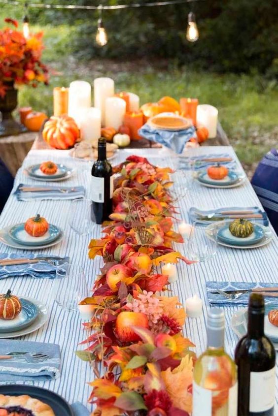 a relaxed fall wedding tablescape with blue linens, bold fall blooms, apples and pillar candles is a fantastic idea for a wedding