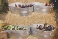 a relaxed rustic wedding drink bar composed of hay, with bathtubs, with a wooden sign is a lovely idea for a rustic wedding