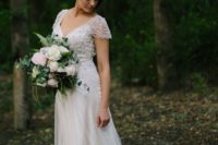 a romantic A-line wedding dress with an embellished bodice, cap sleeves and a pleated skirt plus a train