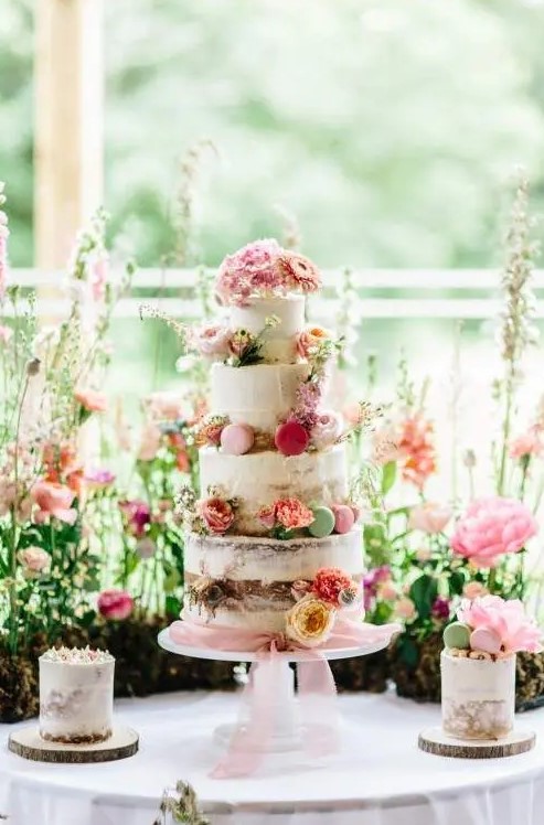 a romantic garden wedding cake - a naked one with bold blooms and colorful macarons plus pink ribbons is wow