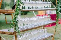 a round and open shelving unit decorated with greenery is a lovely idea for a modern rustic wedding and looks very cool