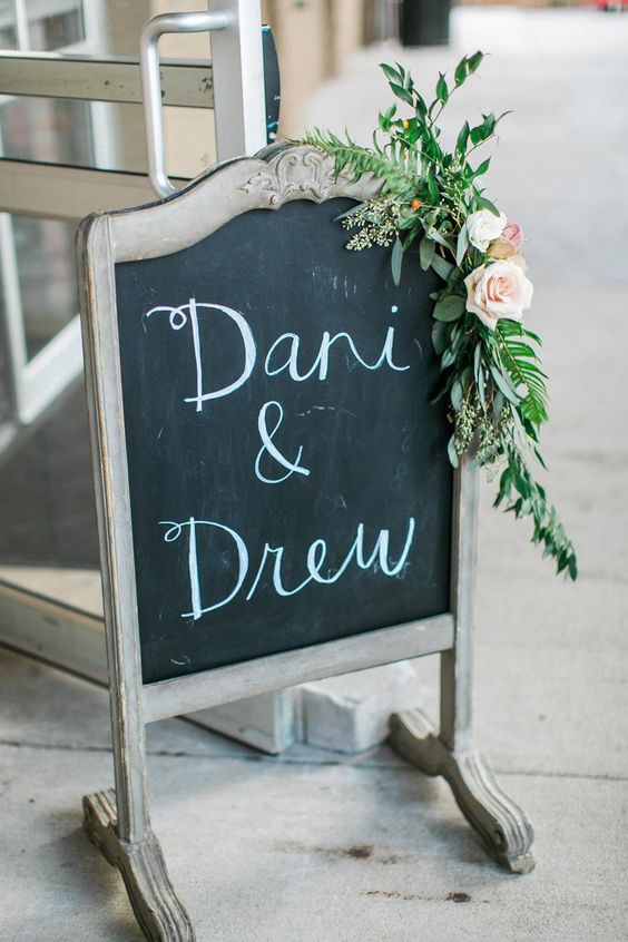 a rustic chalkboard sign  on a vintage stand, with greenery and neutral blooms is a lovely idea for a rustic wedding, and you cna easily DIY one