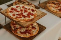 a rustic pizza bar with pizzas on wooden stands is a very simple and cute idea