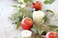 a rustic wedding table runner with eucalyptus, apples and pillar candles is a great idea for a rustic wedding, you can compose it yourself