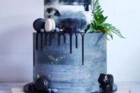 a slate grey wedding cake with navy drip, gold touches, greenery and navy and cream macarons