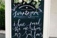 a stylish chalkboard sign in a white frame with calligraphy and pink and neutral blooms and greenery is a lovely idea for a vintage wedding