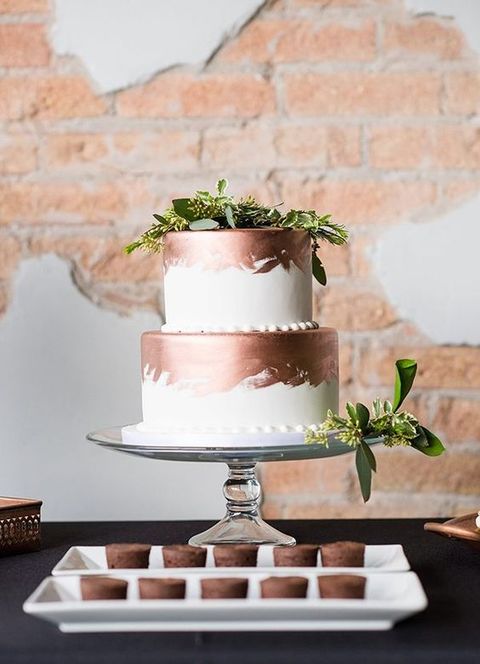 a stylish white and copper brushstroke wedding cake with greenery for a fresher look will fit a modern wedding