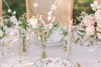 a super delicate and chic pastel wedding reception table with cluster centerpieces, cool floral plates and blush candles and gold cutlery