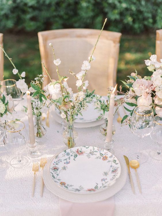a super delicate and chic pastel wedding reception table with cluster centerpieces, cool floral plates and blush candles and gold cutlery