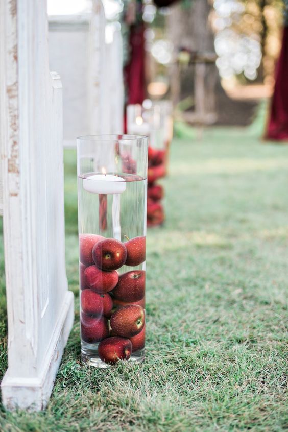 a tall glass vase filled with apples and a floating candle is a lovely decor idea for a fall wedding, and you can DIY it