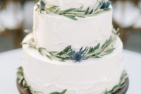 a textural white wedding cake with olive greenery and thistles for a rustic wedding