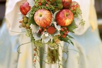 a unique wedding bouquet of apples, berries, greenery and pale foliage is a lovely idea for a fairytale wedding