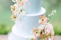 a very delicate pastel blue wedding cake with fresh white and peachy blooms and baby’s breath is amazing for a garden wedding