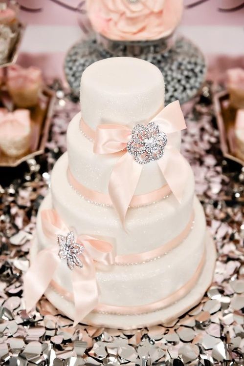 a vintage glitter wedding cake with pink ribbon and pink ribbon bows, with embellished brooches is a stylish solution for a wedding