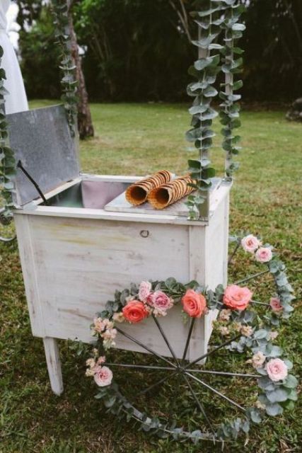 a vintage ice cream trolley with flower-covered wheels and greenery is a lovely idea for a relaxed and laid-back wedding