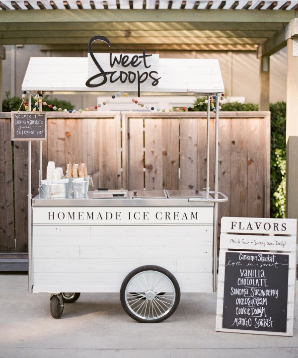 a vintage white ice cream trolley with a pompom banner, with ice cream cones and a little menu is a classic idea for any wedding