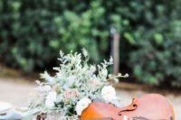 a violin dressed up with greenery and blooms will be an amazing and refined wedding centerpiece
