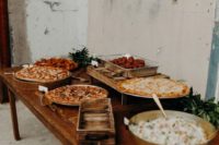 a vintage rustic pizza bar with lots of pizzas on stands and with marks plus greenery and salad in a bowl