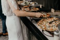 a wedding pizza bar with wire pizza stands, marks on each pizza and soem condiments