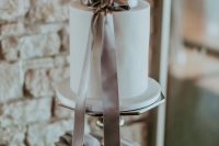 a white buttercream wedding cake with a grey silk ribbon bow is a very chic and stylish idea for a modern wedding