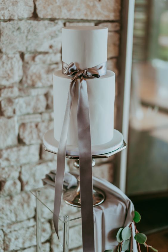 a white buttercream wedding cake with a grey silk ribbon bow is a very chic and stylish idea for a modern wedding