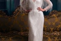 a white long fringe sheath wedding dress with an illusion neckline and sleeves and a beaded bodice plus an embellished headpiece