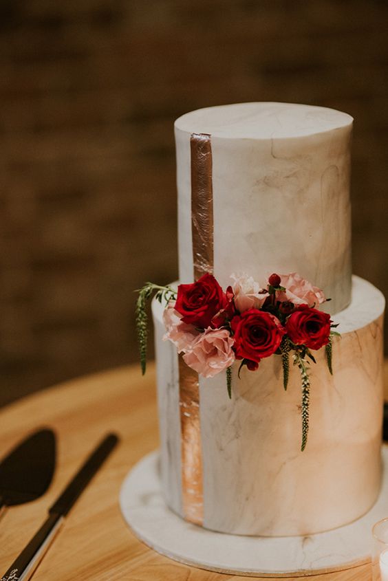 a white marble wedding cake with copper leaf stripes, pink and red blooms is a chic and bold idea for a modern wedding