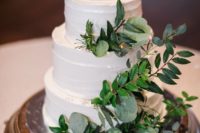 a white textural wedding cake with lush greenery and leaves for a rustic or woodland wedding