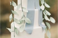 a white wedding cake with a sugar dusty blue ribbon bow and sugar leaves for a spring or summer wedding