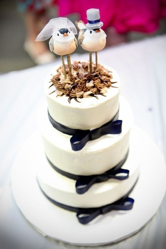 a white wedding cake with black ribbon bows, with fun bird cake toppers is a lovely idea for a whimsical wedding