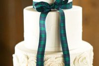 a white wedding cake with plain and a floral tier, with a tartan ribbon bow for a stylish wedding with a Scottish feel