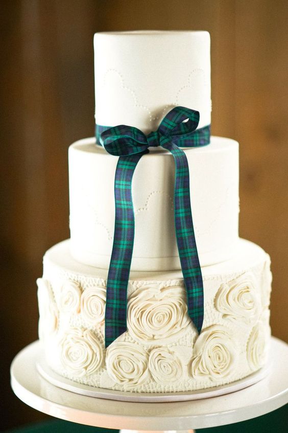 a white wedding cake with plain and a floral tier, with a tartan ribbon bow for a stylish wedding with a Scottish feel
